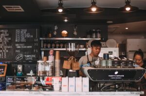 Baristas prepare coffee in a cozy café with a rustic interior design, offering a lively atmosphere.