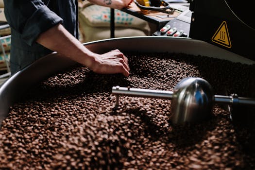 Close-up of a professional roasting coffee beans in an industrial setting, focusing on equipment and beans.