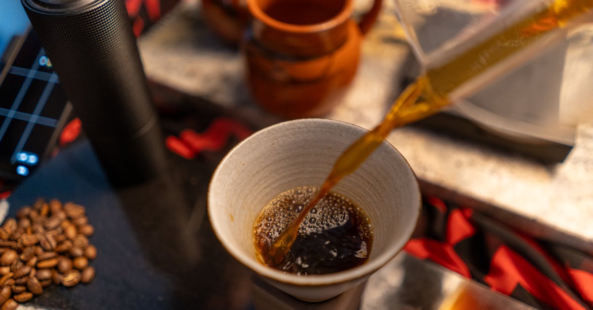Close-up of a pour over coffee brewing process with beans and mugs nearby for a rich coffee experience.
