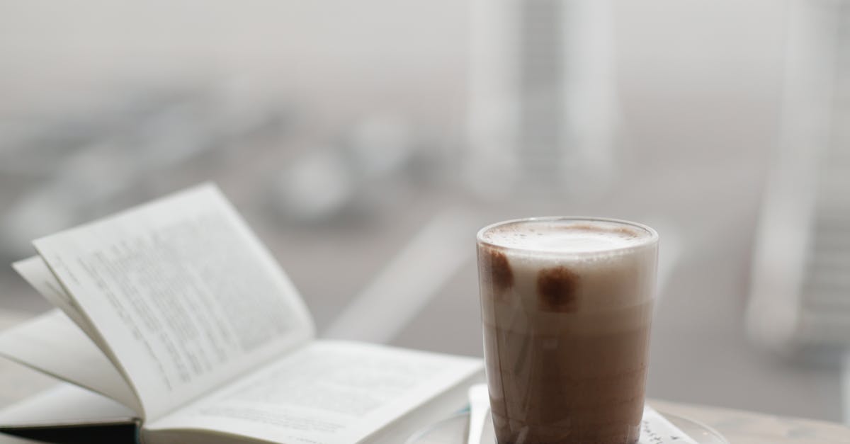 A warm coffee sits beside a notebook and smartphone on a foggy day.