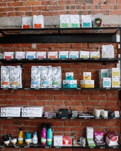 Brick wall shelving in a café with various coffee products and modern decor.
