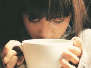 Woman savoring the aroma of a hot coffee cup in a cozy setting.