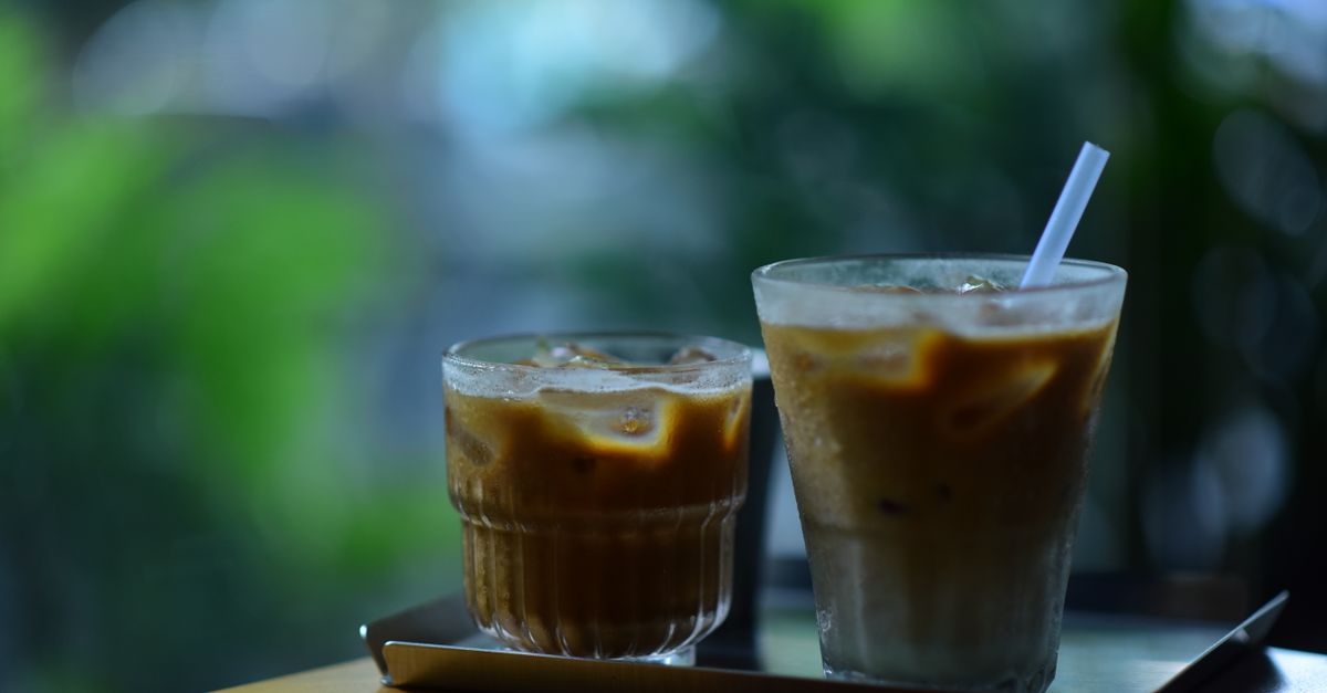 Two chilled iced coffees with a straw on a table, perfect for a warm day.